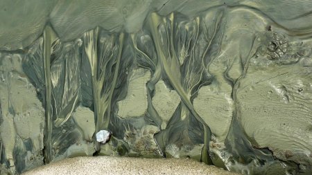 L’eau de fonte sculpte les boues glaciaires sur le rivage.