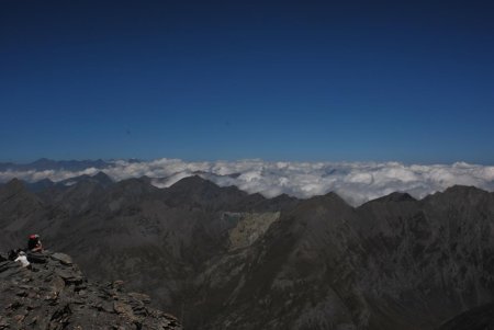 Vue du sommet vers le nord au loin. Une chaîne se détache au-dessus des nuages, le Cervin ou le mont Rose ?